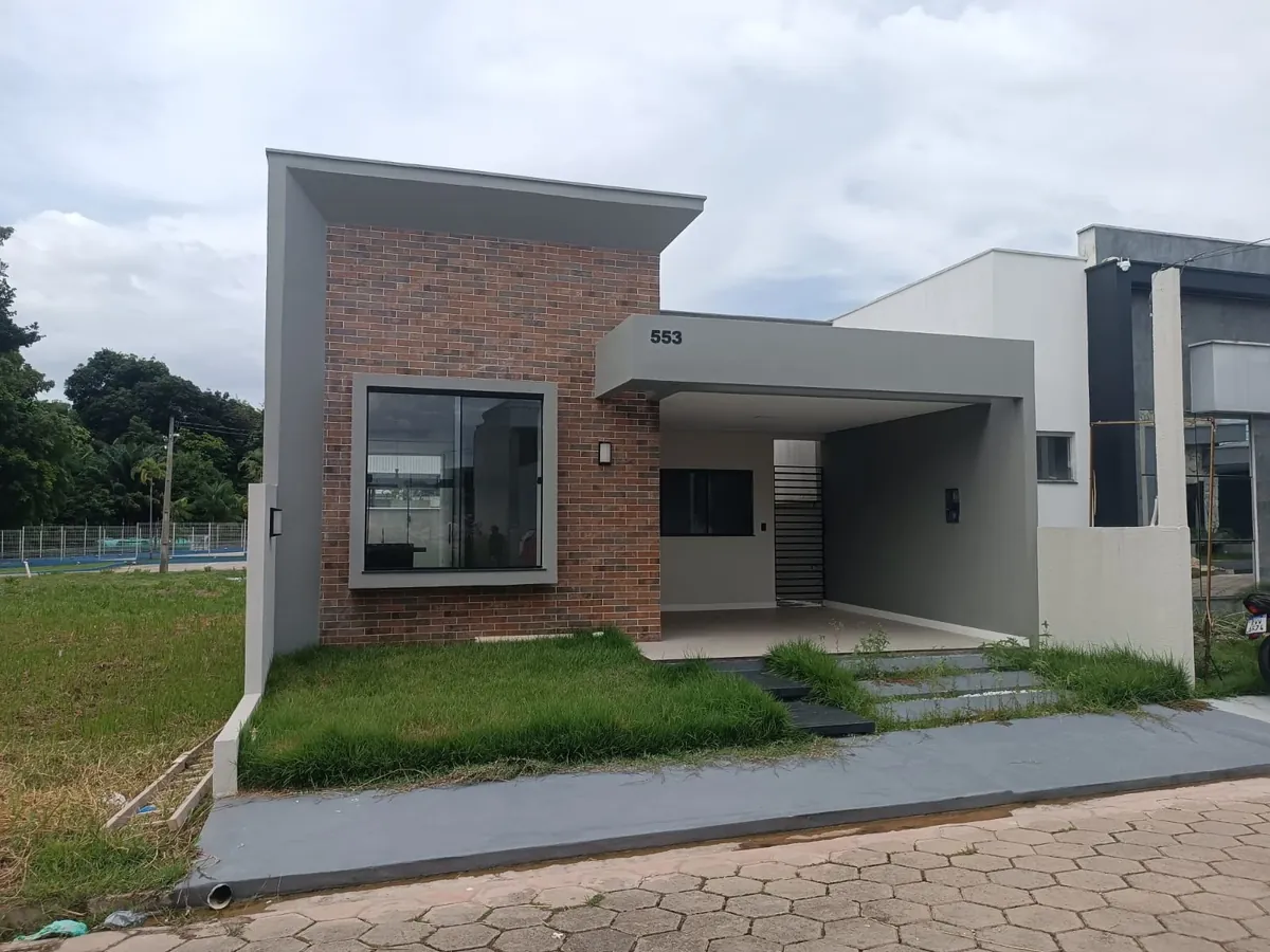 Fachada da casa 553 do Residencial Porto Marina, com painel de tijolinho aparente e garagem coberta