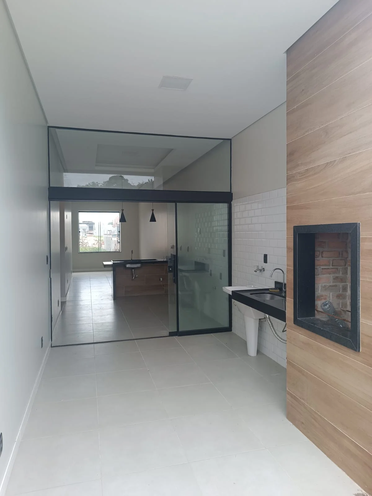 Área gourmet: churrasqueira em alvenaria, painel em madeira e bancada com tanque