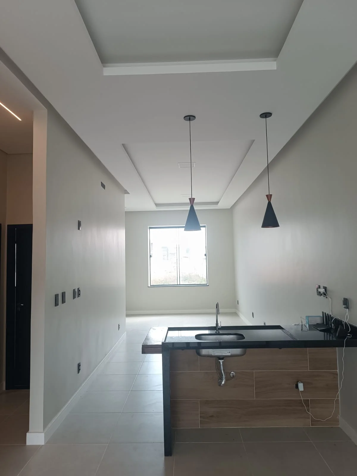 Cozinha americana com bancada em granito preto e pendentes sobre a ilha
