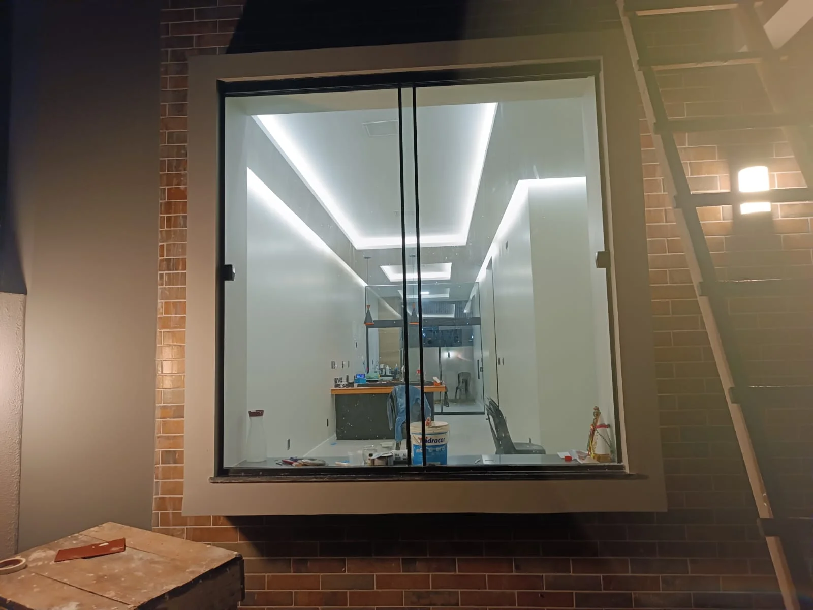 Esquadria panorâmica da sala assentada no painel de tijolinho, vista externa