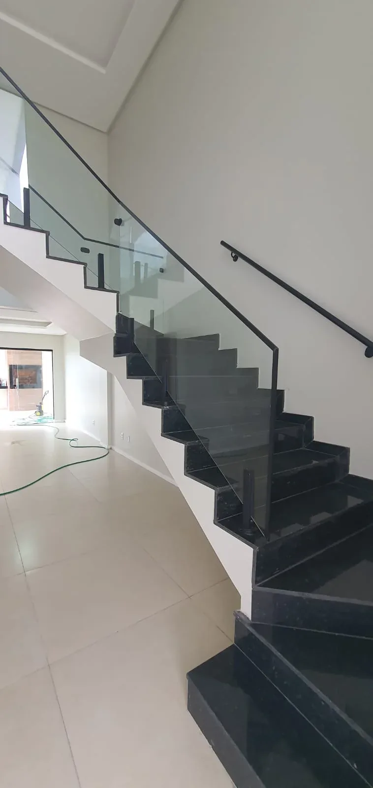 Escada em granito preto vista de perfil, com corrimão metálico
