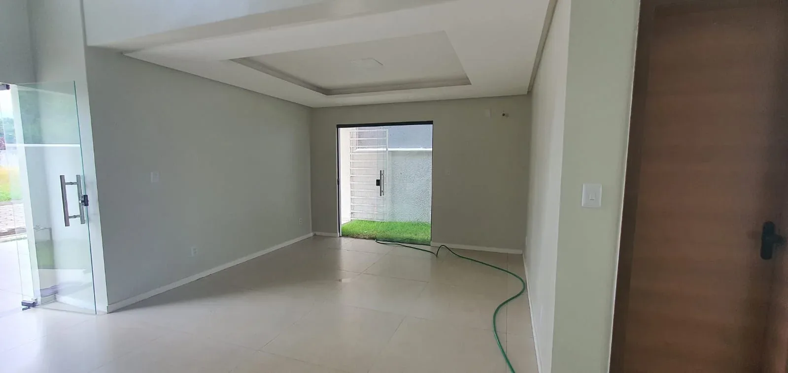 Sala ampla com forro rebaixado e porta de vidro para o quintal