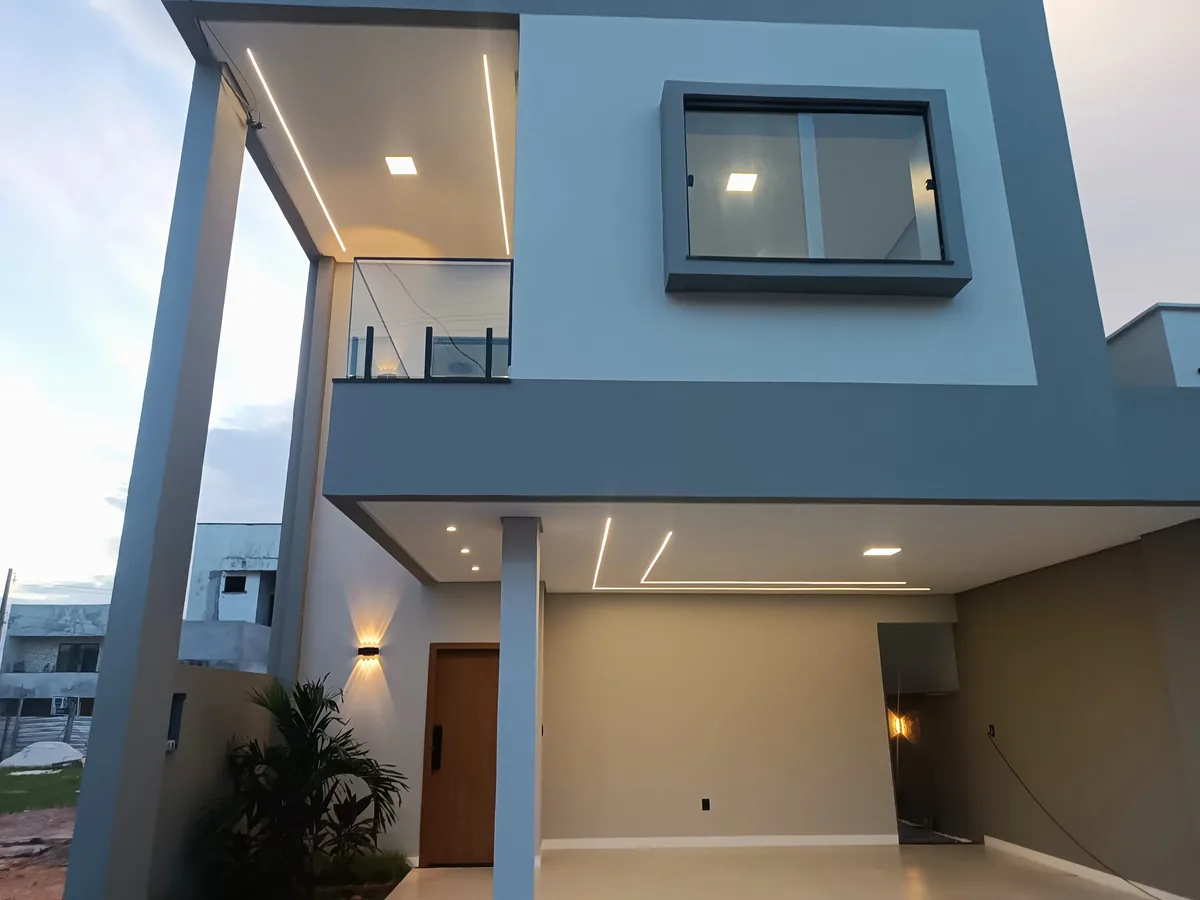 Fachada iluminada ao entardecer da casa K19 no Quartzo Condomínio Verde, sobrado com garagem coberta