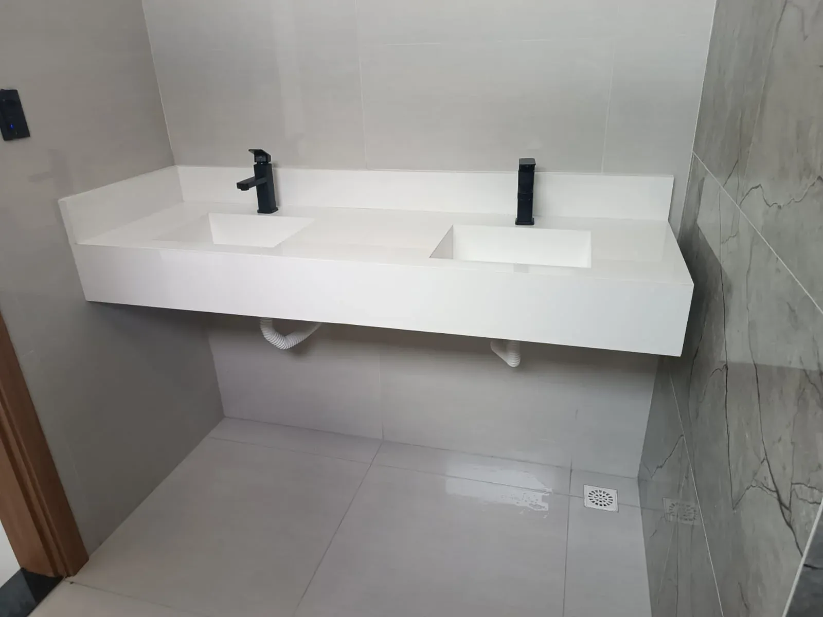 Lavabo com bancada dupla em porcelanato branco e parede marmorizada