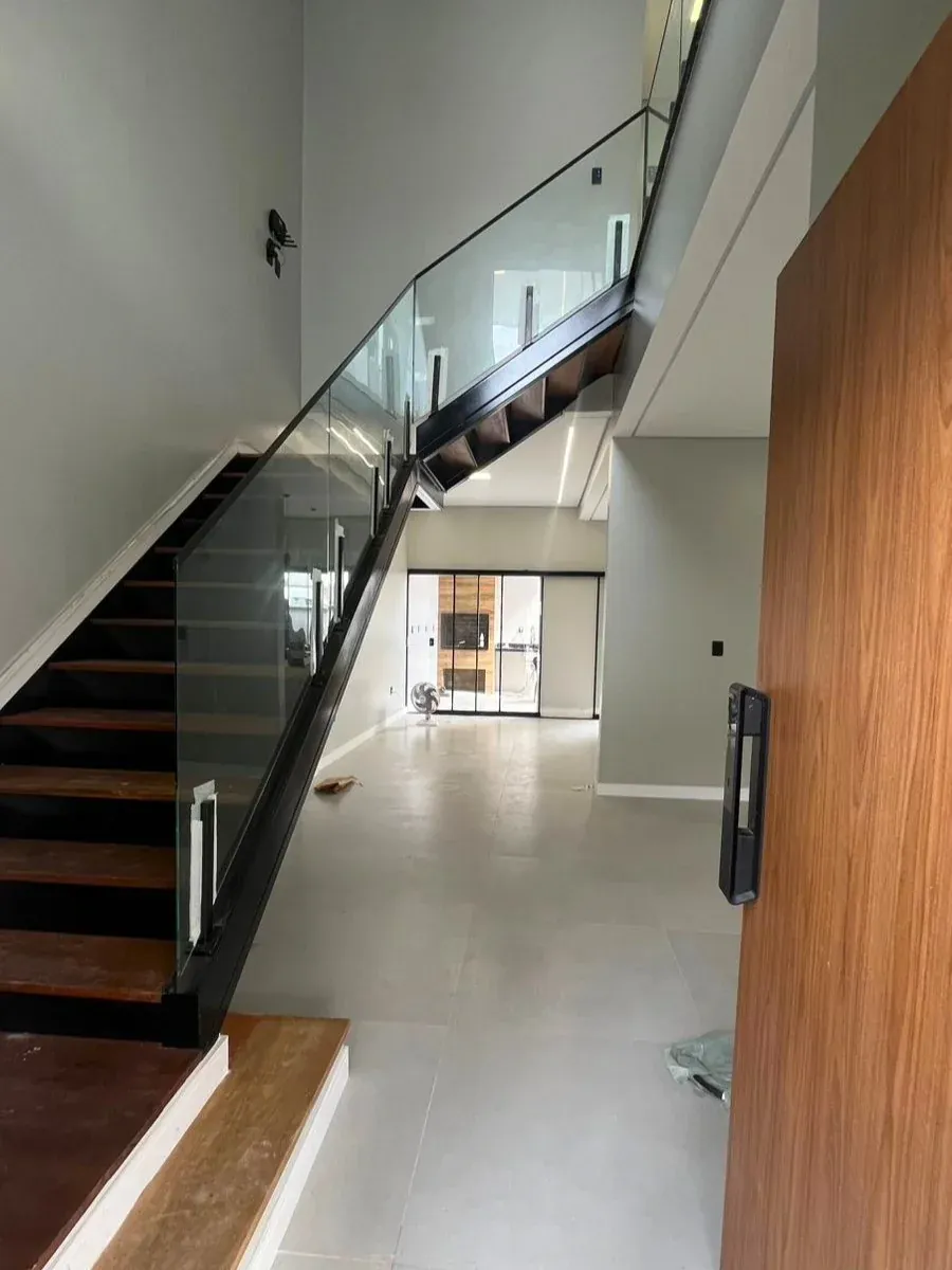 Escada em madeira e aço com guarda-corpo de vidro, vista da entrada