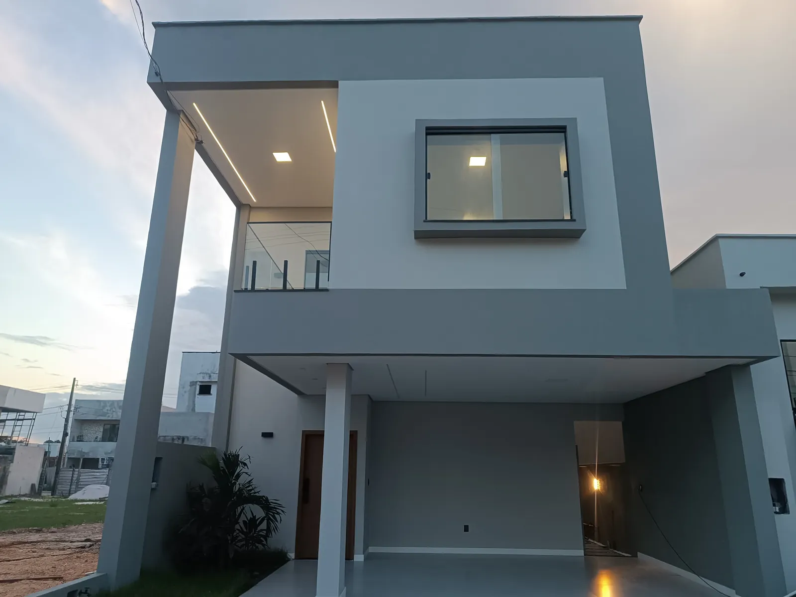 Fachada frontal do sobrado, com sacada em vidro e esquadrias pretas