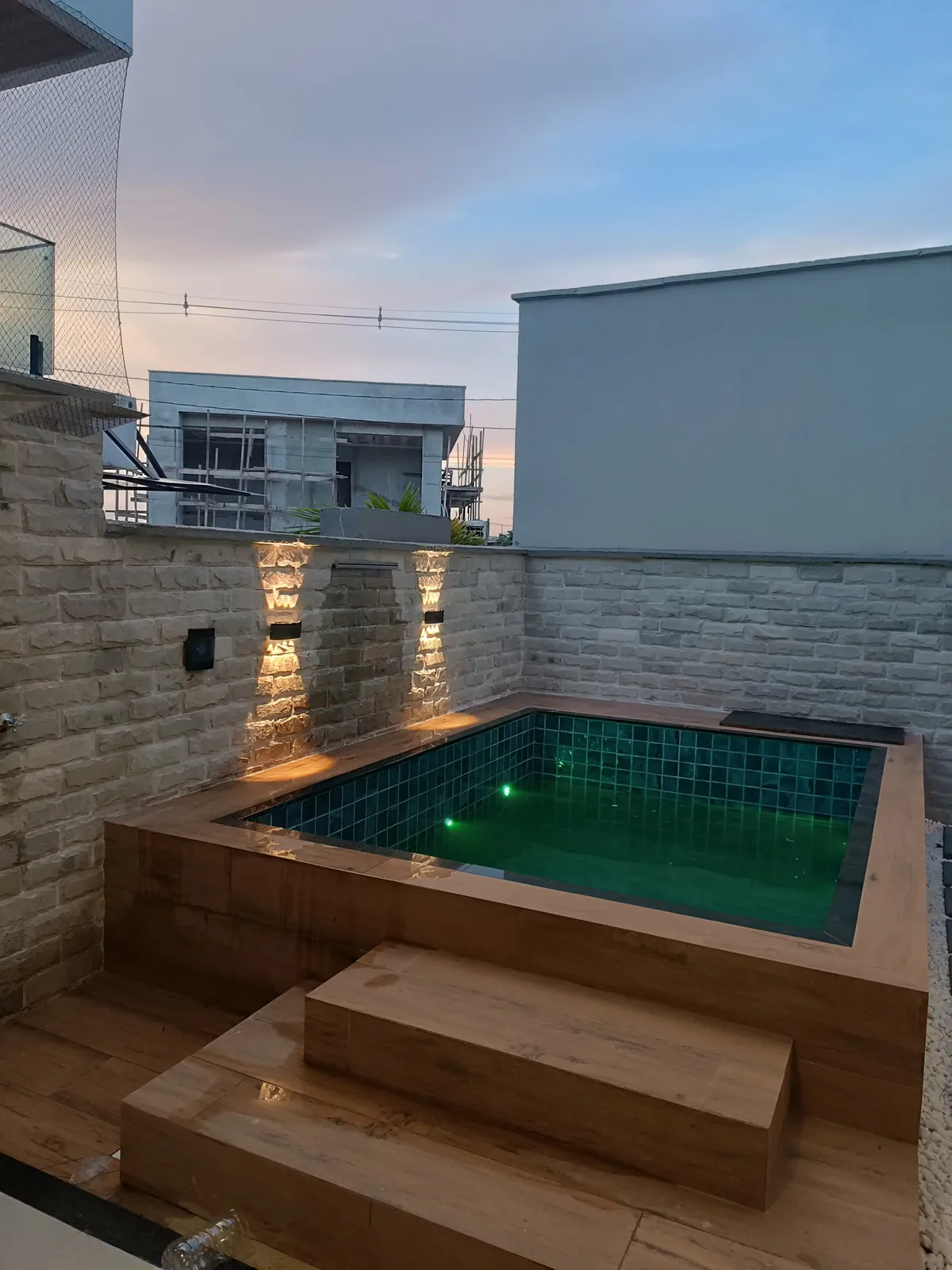 Piscina com deck e degraus em porcelanato amadeirado, vista lateral