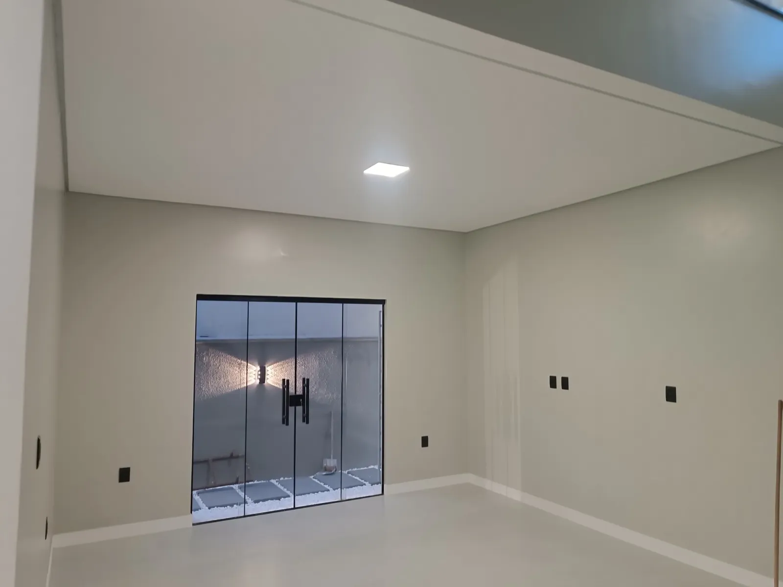 Sala ampla com porta de vidro para jardim de inverno iluminado