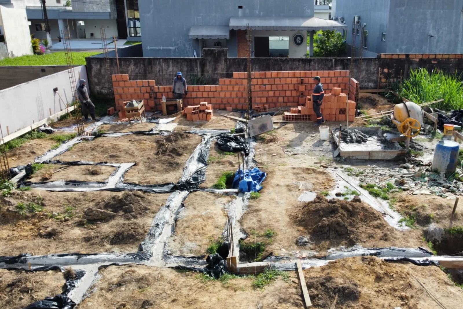 Assentamento dos blocos cerâmicos do muro divisório, com betoneira em operação