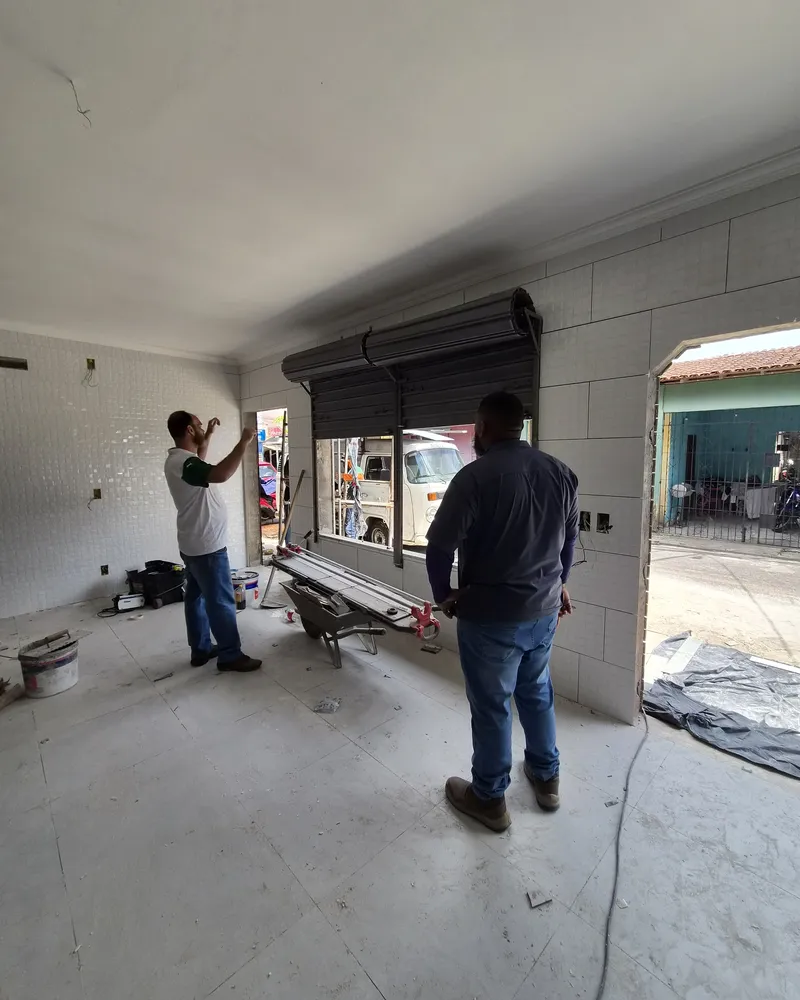 Salão no meio da obra, com a porta de enrolar instalada e um vão em arco para a rua