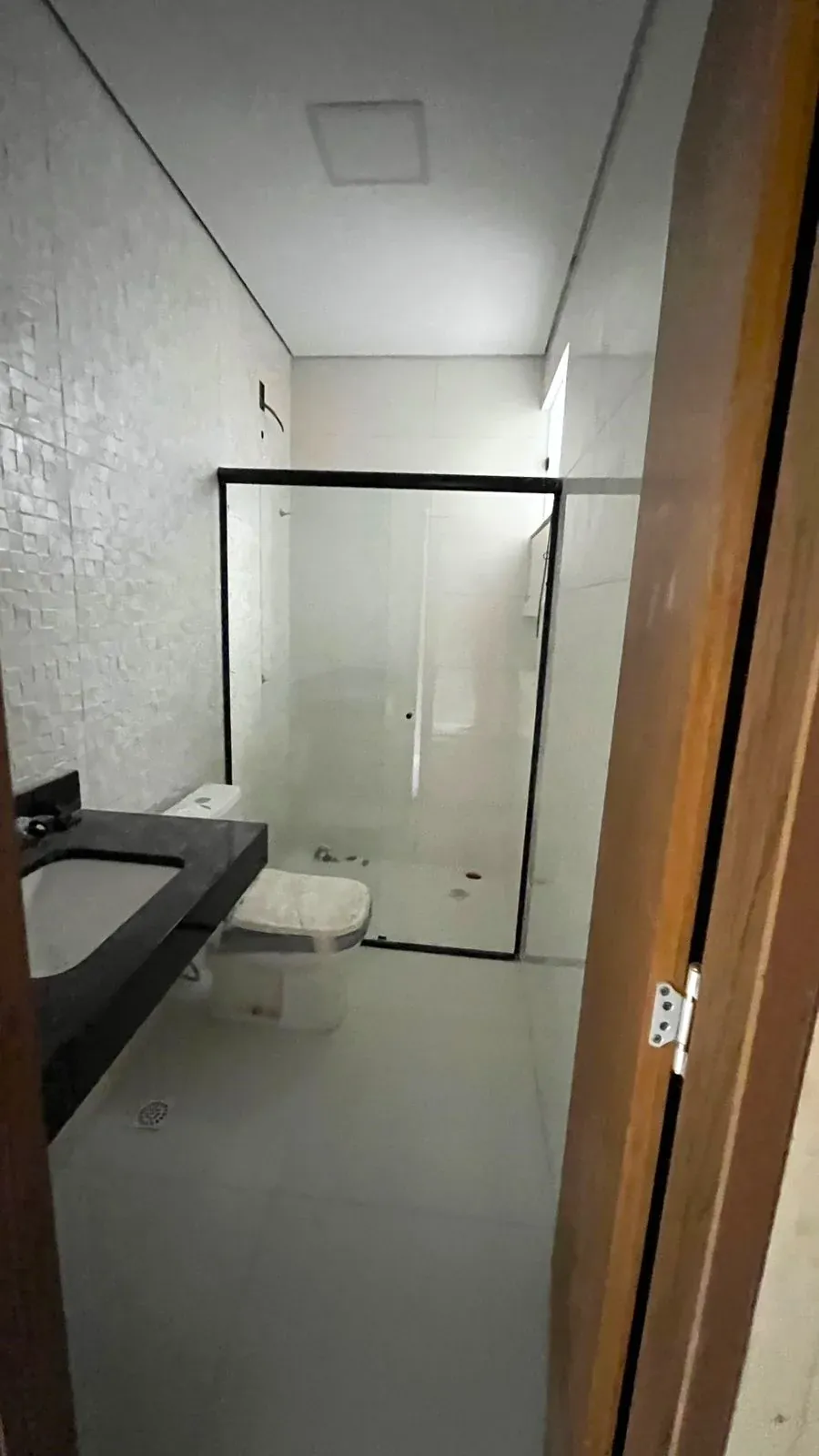 Banheiro com box de vidro e bancada em granito preto