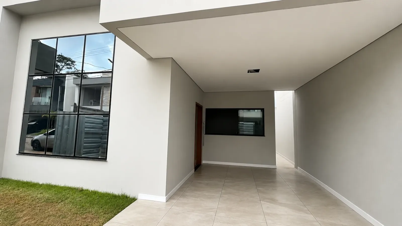 Área coberta com esquadria quadriculada e porcelanato, junto ao acesso