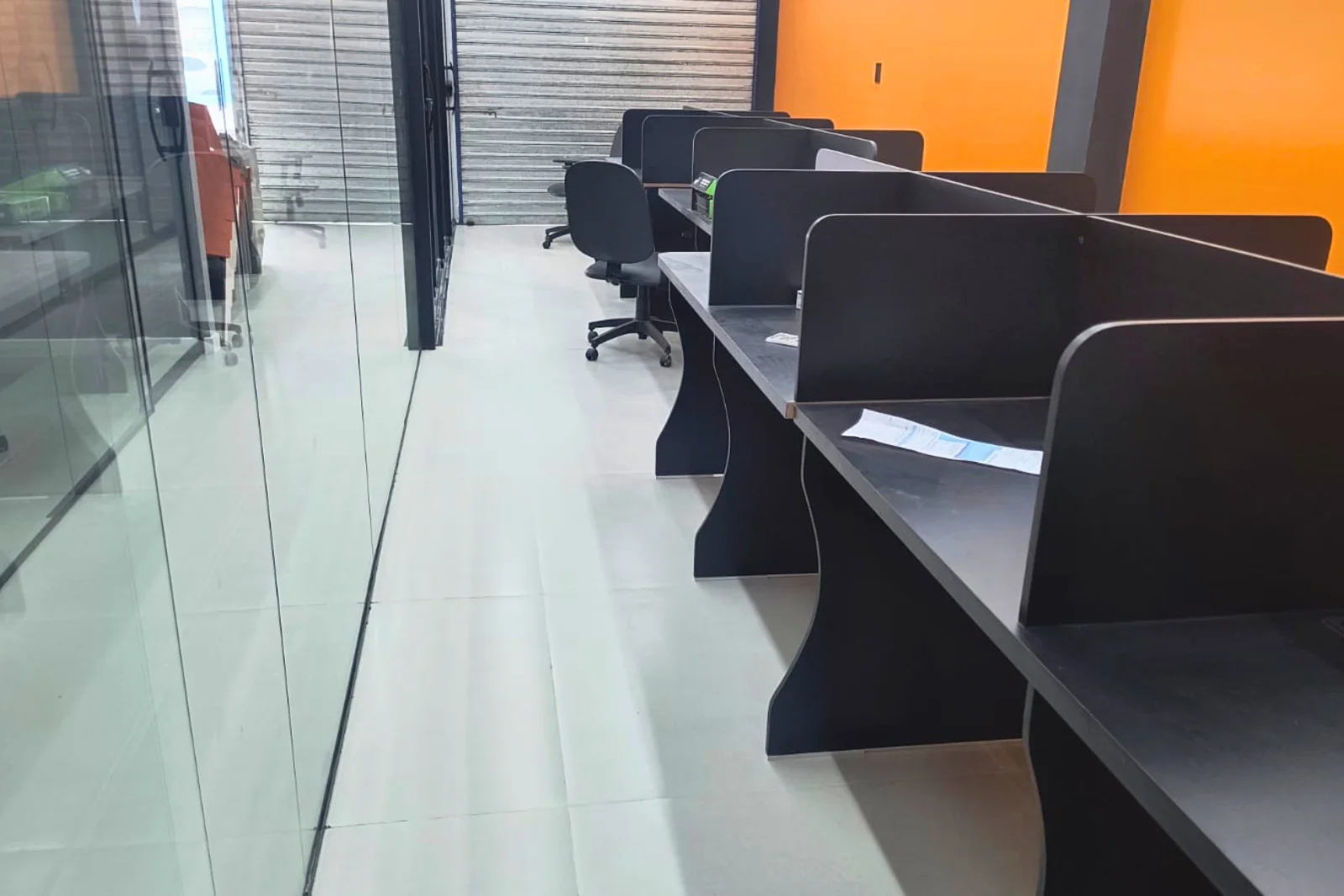 Área de trabalho aberta, com divisórias de vidro e estações em linha