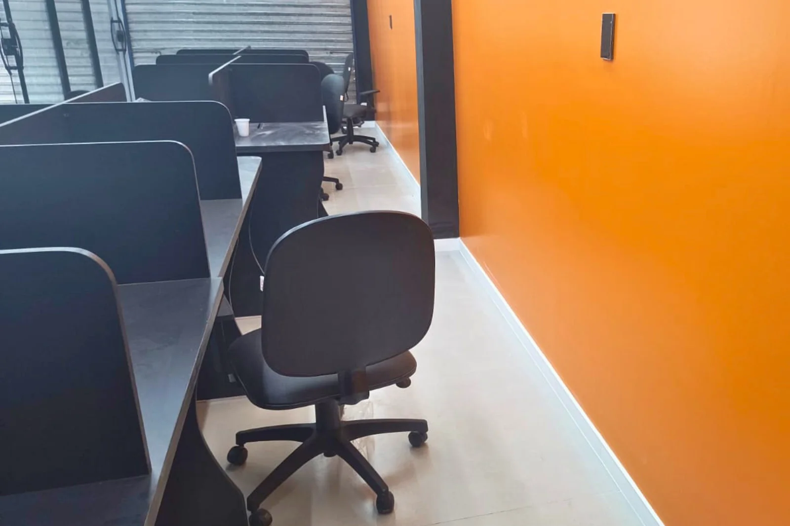 Estações de trabalho e parede laranja do escritório reformado no Sansol Cidade Nova