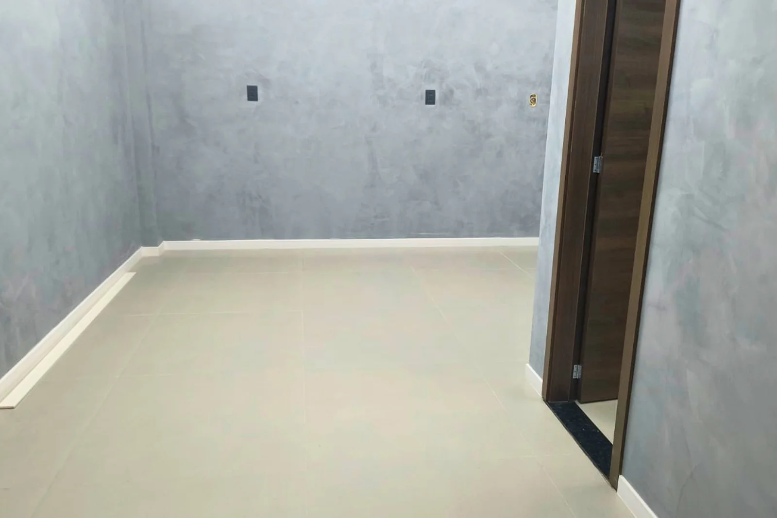 Sala após a reforma: marmorato cinza, porcelanato claro e rodapé alinhado